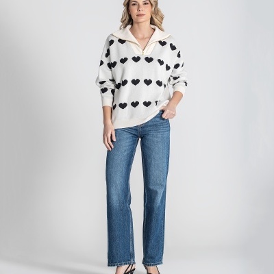 Mulher com camisola branca de corações pretos, jeans azuis e sapatos pretos de salto