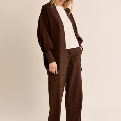 mulher vestindo cardigan castanho, calças largas castanhas, t-shirt branca e sapatos marrons