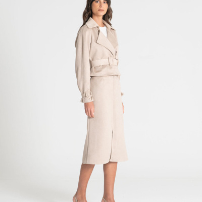 Mulher com conjunto bege de casaco e saia, sapatos bege em fundo branco