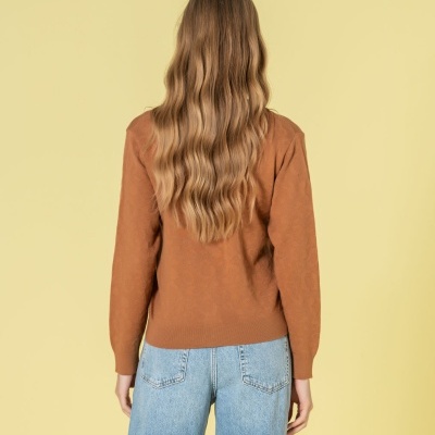 Mulher de costas com pulôver castanho e jeans azuis