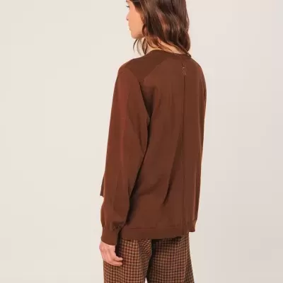 Pessoa vista de costas com camisola castanha e calças à quadrados castanho e preto.