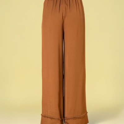Calças largas castanhas com cinto fino castanho em fundo bege