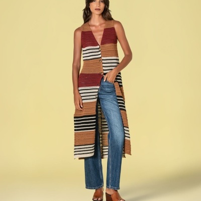 Mulher a usar colete longo de crochet às riscas, jeans azuis e sandálias castanhas de plataforma