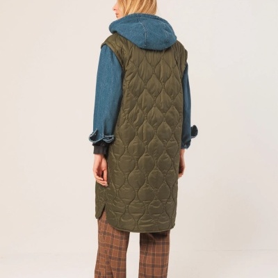 Pessoa de costas com colete verde-oliva acolchoado e casaco azul com capuz