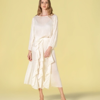 Mulher com vestido longo branco de tecido leve e sapatos brancos