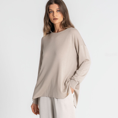 Mulher a usar camisa manga comprida bege e calças largas beige