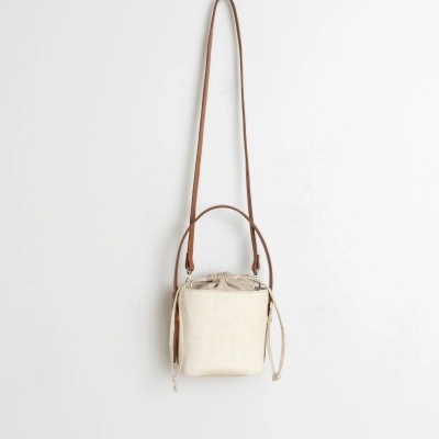 Mala pequena bege com alças castanhas pendurada na parede