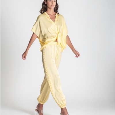 Conjunto amarelo feminino camisa nó frontal calças elásticas com detalhes sandálias transparentes.