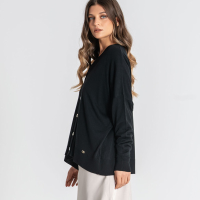 Mulher veste cardigã preto com botões e saia branca em fundo branco