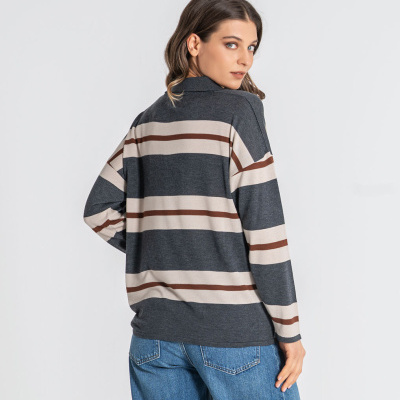 Camisola de malha às riscas cinza, bege e castanho com jeans azuis.