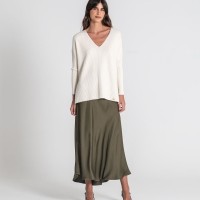 Modelo com camisola branca de malha e saia verde oliva comprida e fluida