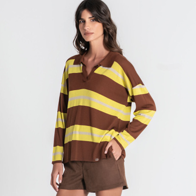 Mulher com camisola de manga comprida às riscas amarelas e castanhas e calções castanhos