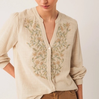 Blusa bege bordada com flores em verde e amarelo, botões brancos.