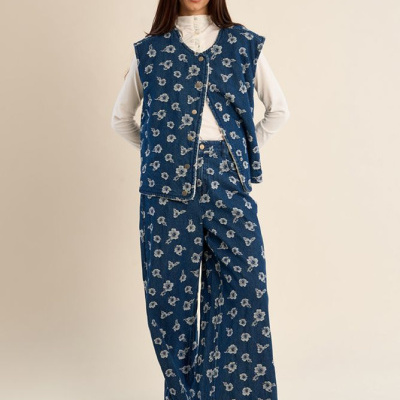 Conjunto feminino em tecido azul com padrão de flores brancas, colete com botões e calças largas.