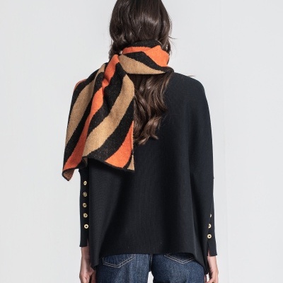 Mulher de costas com camisola preta e cachecol riscado laranja, preto e bege