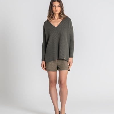 Mulher com camisola cinza escuro de malha e calções verde-oliva de camurça