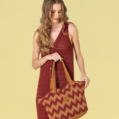 Mulher com vestido crochê vermelho e mala padrão zigzag vermelho e bege