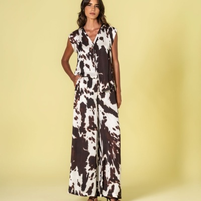 Conjunto feminino padrão animal preto e branco com blusa sem mangas e calças largas em fundo amarelo.