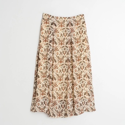 Saia longa floral bege com padrão castanho pendurada na parede branca