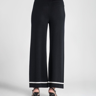 Calças pretas largas com detalhe branco na bainha vistas de costas