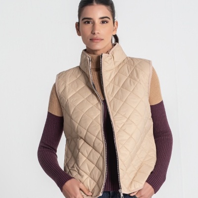 Colete acolchoado bege com fecho, mulher com camisola castanha e roxa