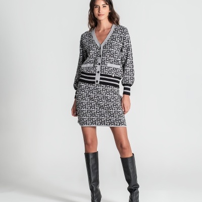 Mulher com conjunto de cardigan e saia padrões preto e branco com botas pretas num fundo branco