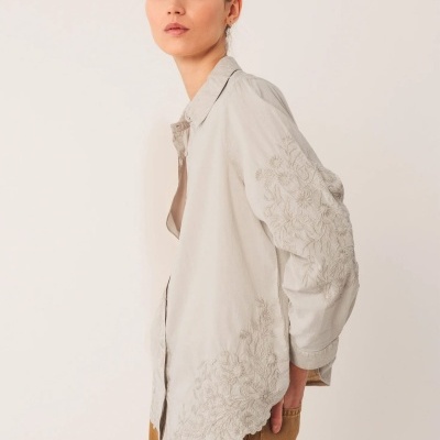 Blusa bege com bordados florais subtis vista de lado