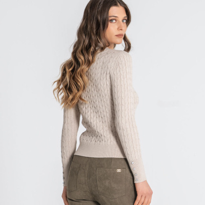 Mulher de costas com camisola bege de malha e calças castanhas de camurça