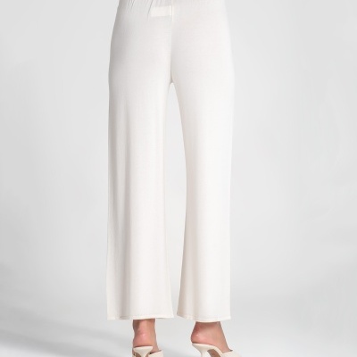 Calças brancas largas e elásticas vistas de costas, usadas com sapatos de salto altos brancos