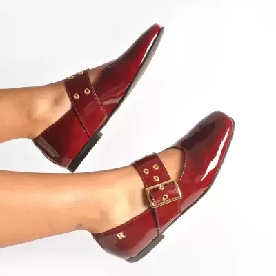 Sapatos vermelhos brilhantes tipo mocassins com fivela dourada e detalhes em ilhós dourados