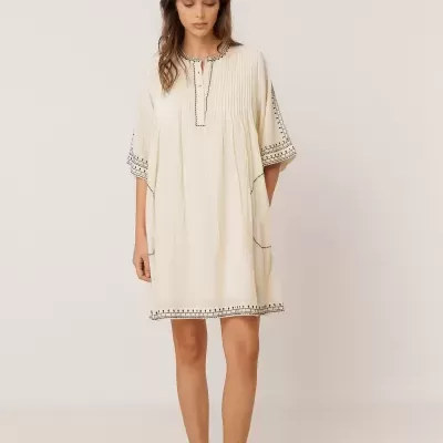 Vestido curto bege com bordados pretos em modelo feminino