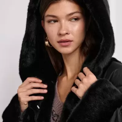 Mulher a usar casaco preto com capuz de pelo sintético negro e suéter castanho claro
