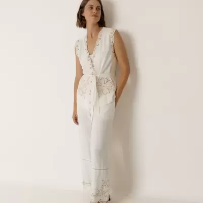 Macacão branco feminino com bordados florais e cinto, usado com sandálias castanhas