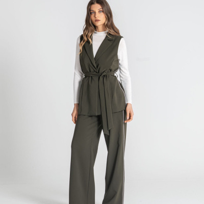 Mulher a usar conjunto verde escuro com colete e calças largas e camisola branca de manga comprida