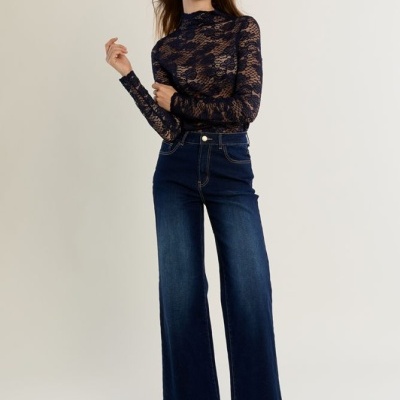 Mulher com blusa de renda preta e calças de ganga azul escuro largas
