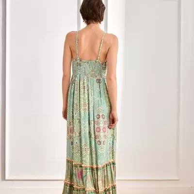 Vestido longo estampado em padrão floral e geométrico com alças finas e folhos na parte inferior, visto de costas.