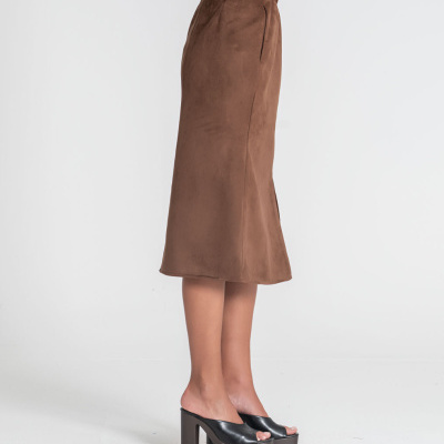 Saia midi castanha de tecido camurça vista de perfil numa modelo com sapatos pretos de salto alto em plataforma