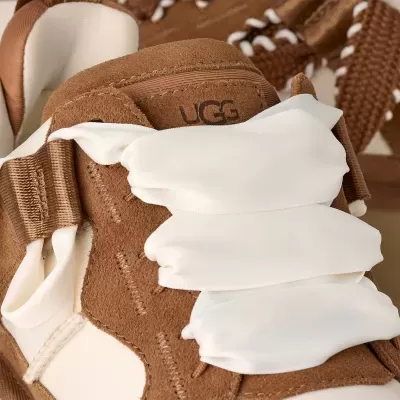 Sapatilha castanha da marca UGG com atacadores brancos largos em close-up