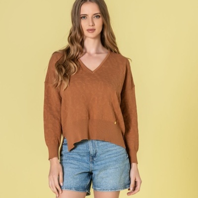 Mulher com camisola castanha de malha e calções de ganga azul