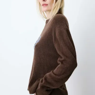 Camisola castanha de malha felpuda com detalhe azul usada por mulher com jeans azul