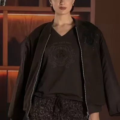 Mulher com casaco, camisola, calças florais rendadas e boné castanho