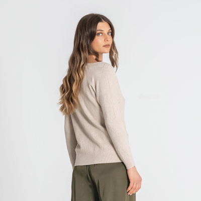Mulher de costas com camisola bege de malha e calças largas verde-oliva