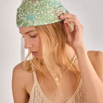 Lenço de cabeça floral verde e azul usado por mulher com camisola creme