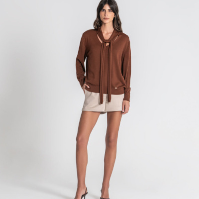 Mulher com camisola castanha, short bege e sapatos de salto castanhos