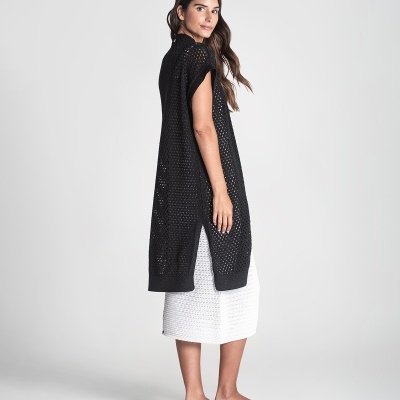 Mulher com colete preto de malha e vestido branco
