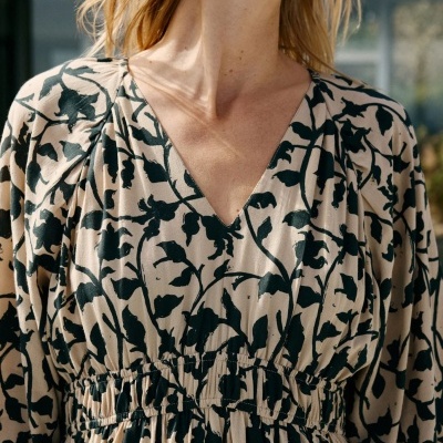 Vestido feminino bege com padrão floral preto e decote em V com cintura ajustada.