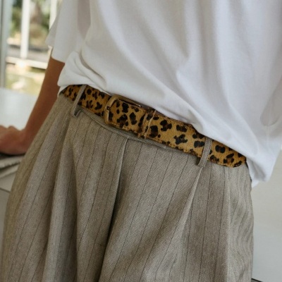 Cinto com padrão animal castanho em calças de tecido cinza e camisa branca
