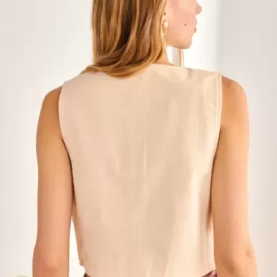 Mulher de costas a usar colete bege e saia com padrão geométrico