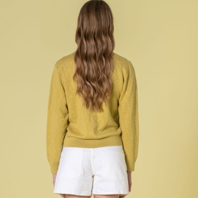 Vista traseira de pessoa com pulôver amarelo texturizado e calções brancos