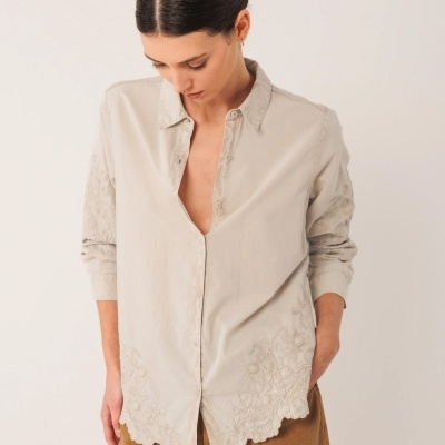 Camisa bege feminina com bordados florais e calças mostarda